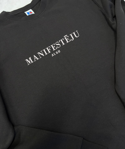 Izšūts teksts “manifestēju” uz unisex džempera