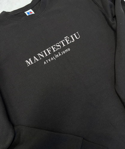 Unisex džemperis ar izšūtu tekstu “manifestēju”