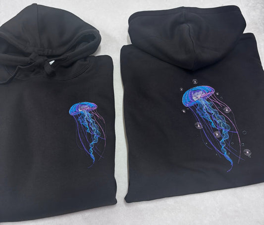 Medūzas izšuvums uz melna unisex hūdija krūšu daļā