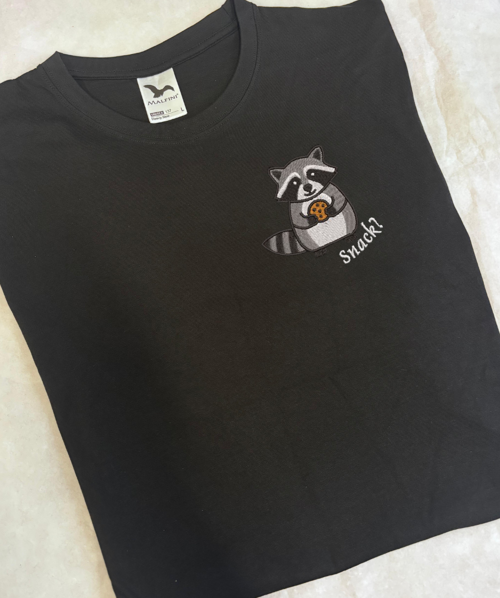 Izšūts jenots uz melna unisex T-krekla